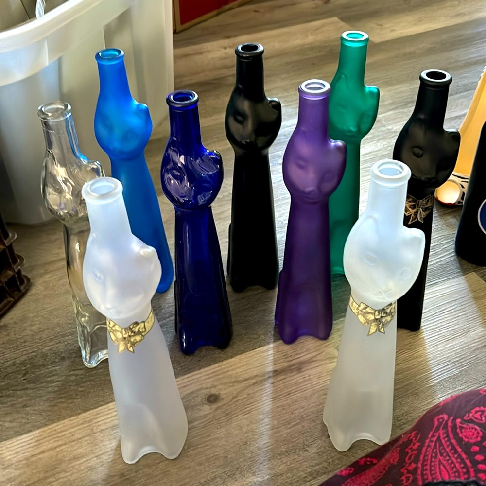 9 empty kitty wine bottles of various colours.
